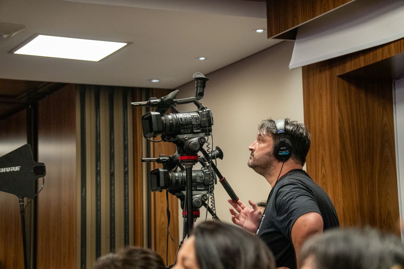 Profesional operando una cámara durante un evento interior; fotografía de referencia